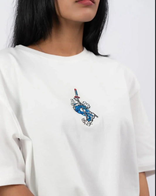 Woman wearing white t-shirt with embroidered blue sword and cloud design on chest