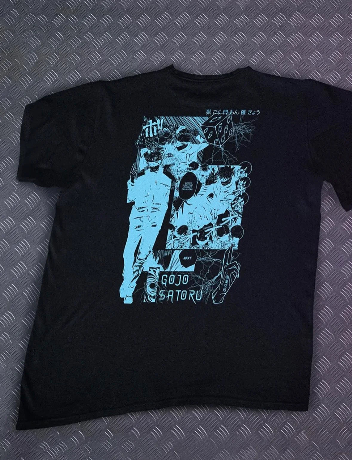Black T-shirt with blue Gojo Satoru manga-style graphic and Japanese text on diamond plate background